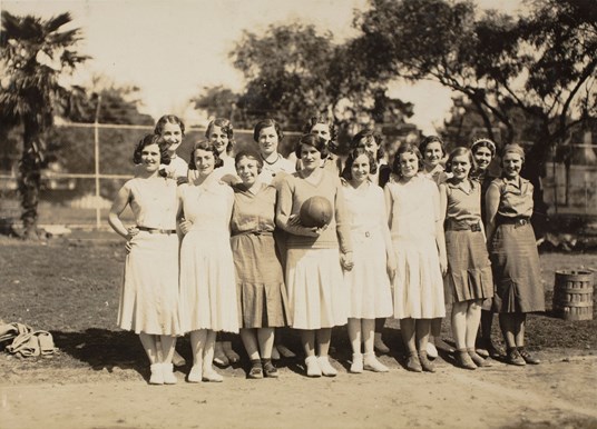 Female sports team. Person centre front is holding a ball.