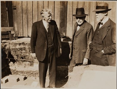 Three men in suits, two wearing hats.