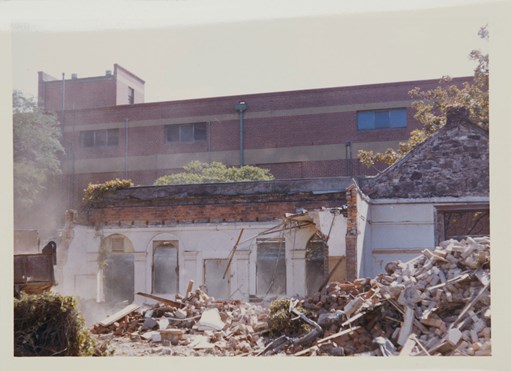 Building rubble in foreground, partially demolised brick building in background