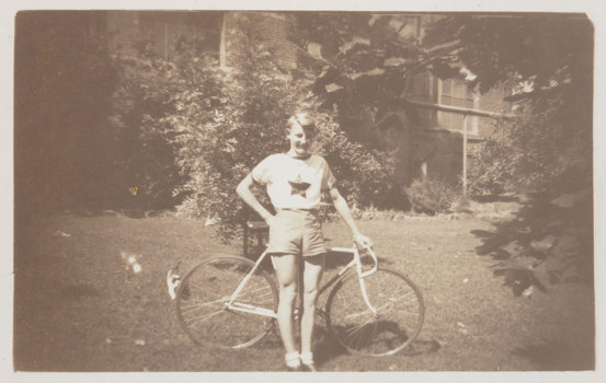 Young man in shorts leaning on bicycle