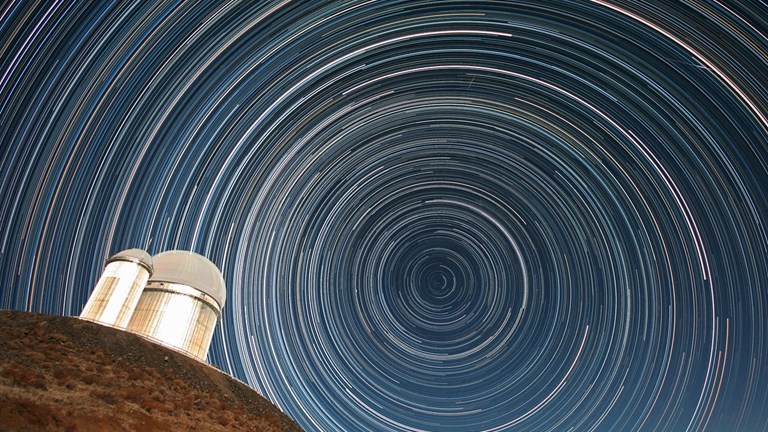 Telescope in front of a full sky of circular star trails