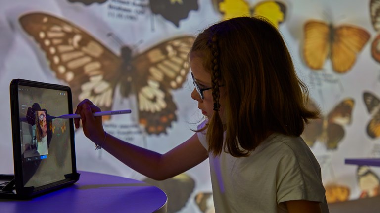 Girl using an ipad to draw a butterfly