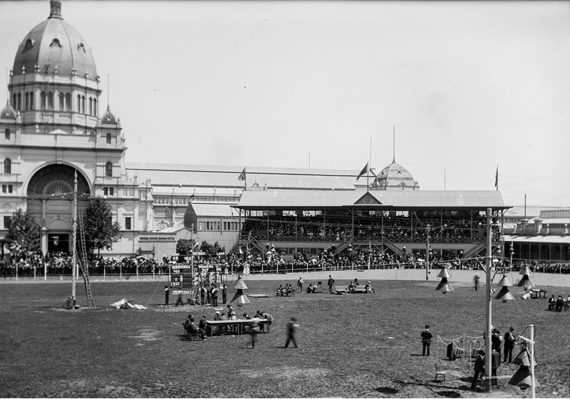A black and white photo of a velodrome with cyclists and spectators