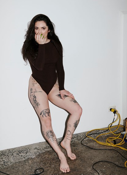 Woman with tattoos eating an apple wear a body suit