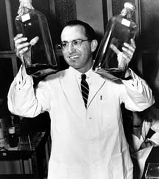 A man in a white lab coat holds two large bottles
