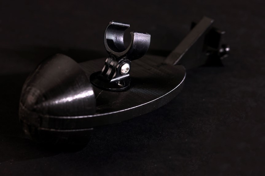 A close up of the bike mount, a dark metallic object against a black background. Light reflects off the metallic edge.