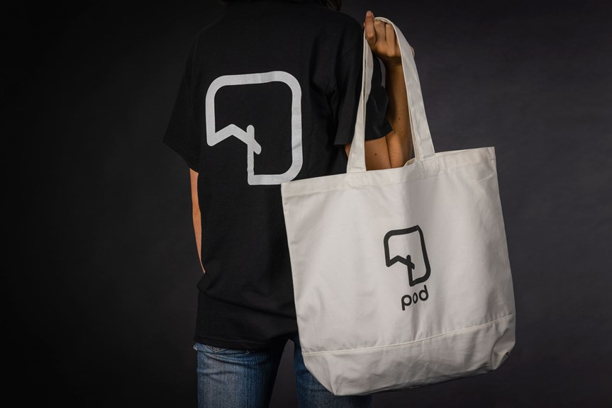 A person is shown holding a tote bag and wearing a t-shirt, both with matching geometric logos. The tote bag has text reading ‘pod’ underneath the logo.