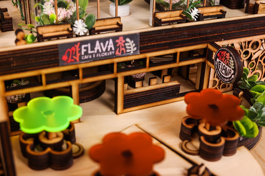 A close-up photograph of an architectural model, with branding that reads ‘Flava Café & Florist’. Large floral designs, seating and geometric embellishments are visible in the model’s design.