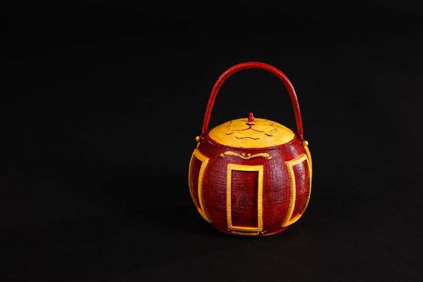 This image shows a 3D printed hotpot model, coloured in vibrant red and yellow tones, set against a black background. 
