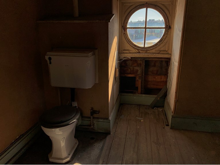 a toilet in a tower with a porthole window looking our over an industrial suburb