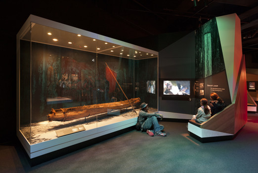 A man and two children watching a video in the First Peoples exhibition