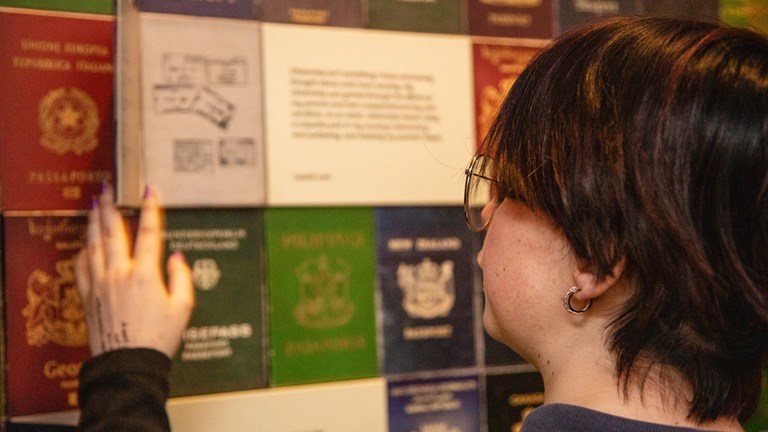 Secondary school student looking at the Passport wall in Identity: Yours, Mine, Ours exhibition in Immigration Museum.
