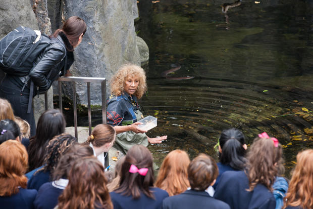 Woman talking to a crowd about the eels in the pond