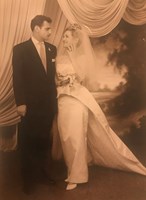 Man in suit with woman wearing tiara, veil, and dress with a train.