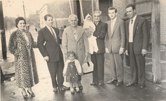 Six adults, one child and a baby  standing on a sidewalk