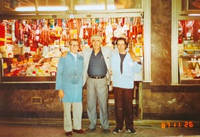 Three men pose in front of a butcher shop