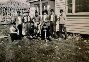 Group of men posed outside a weatherboard house