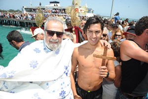 Swimmer holding a cross with a priest next to him