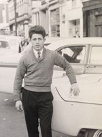 Young man stands proudly next to a 1950s car