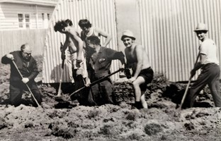 A group of men dig a hole.