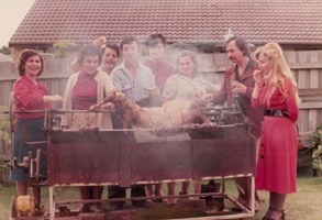 A family spit roast meat in their backyard.