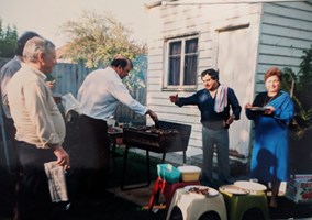 A family cooks meat at a bbq.