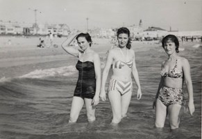 Three woman wade at the beach