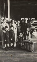 Four adults and four children standing with suitcases.