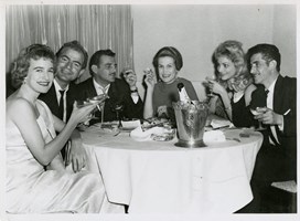 6 people sitting around restaurant table with champagne