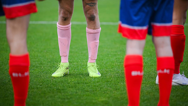 Player legs on the field in bright pink and red football socks at Pride Football Australia, 2025.