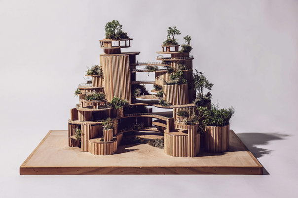 Architectural model of multi-level cylindrical towers with vertical timber cladding, featuring terraced balconies and integrated greenery on each level, mounted on a wooden base.