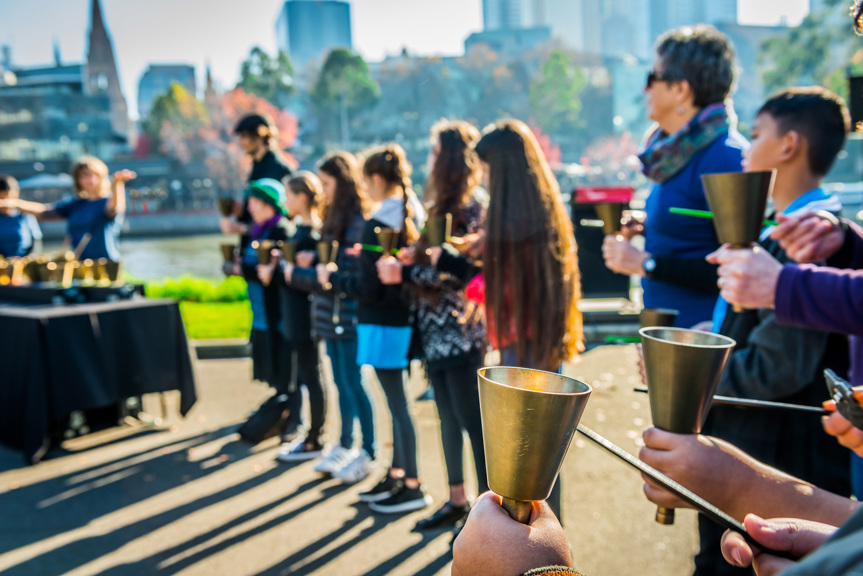 Group standing in a line while playing the Federation Handbells for Inflatable Refugee event in Melbourne