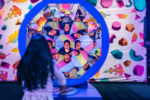 A parent in reflected in a kaleidoscopic pattern as a child looks on.