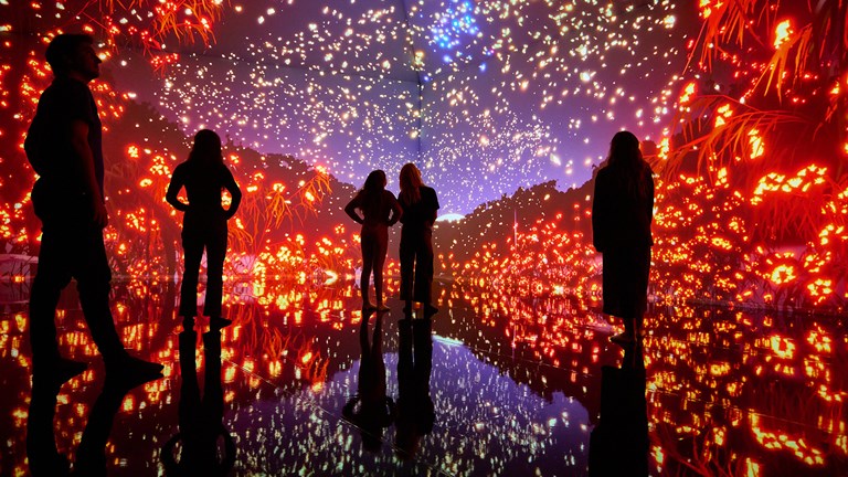 People standing in a room illuminated with colourful projection