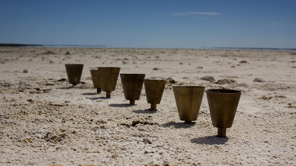 Seven bells in a row in the sand of a salt lake on a clear day