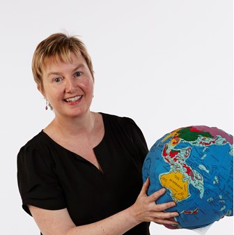 Photograph of a woman smiling and holding a globe