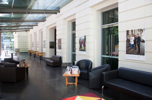 Large room with glass ceiling there are couches, chairs and tables in the room