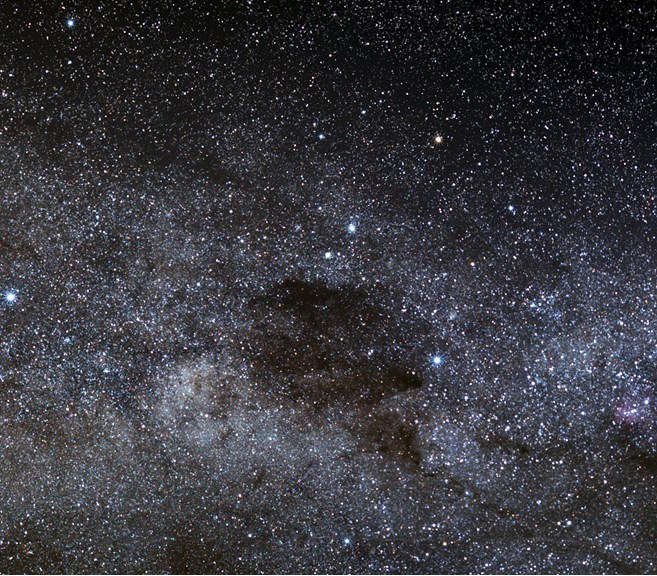 The Southern Cross sits in the foreground of the dense star field of the galaxy which includes the dark interstellar dust cloud, the Coal Sack.
