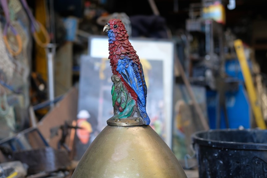 A parrot sculpture perched on a bell