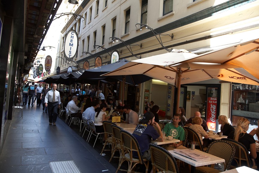 an image of a bustling laneway with people seated at cafe tables