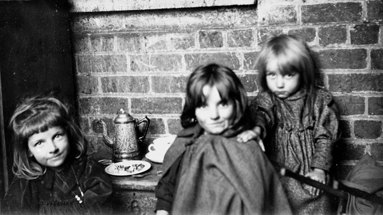 Three young girls looking at the camera. They are playing tea parties