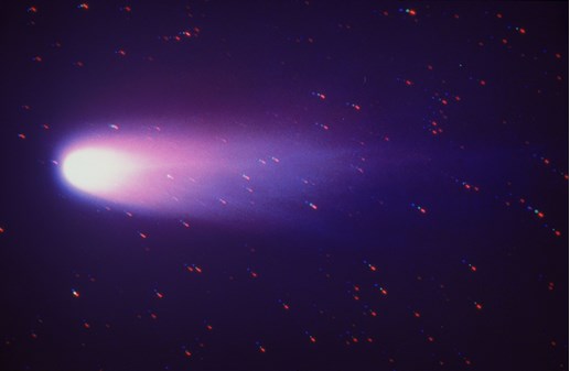 An incandescently bright comet moving from right to left across a starry background
