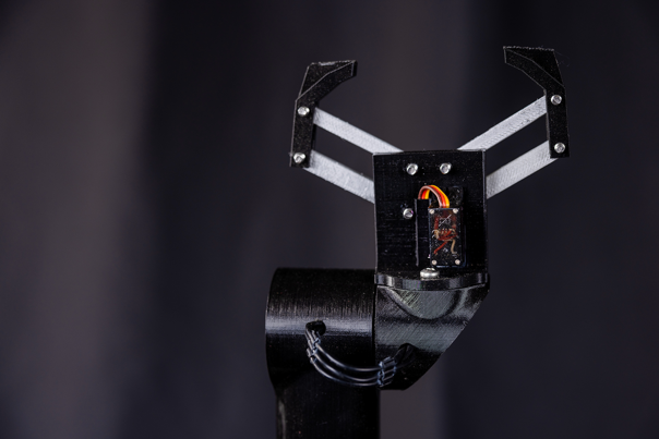 A black robotic arm with two claw like grips protruding at the top.