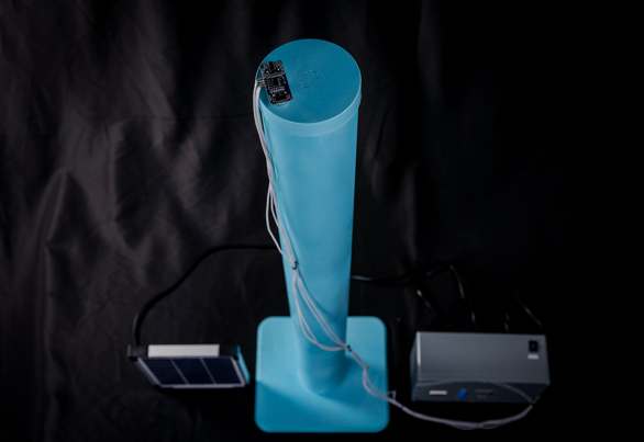 A light blue cylindrical object with a chip and wiring at the top, and two rectangular boxes on both sides.