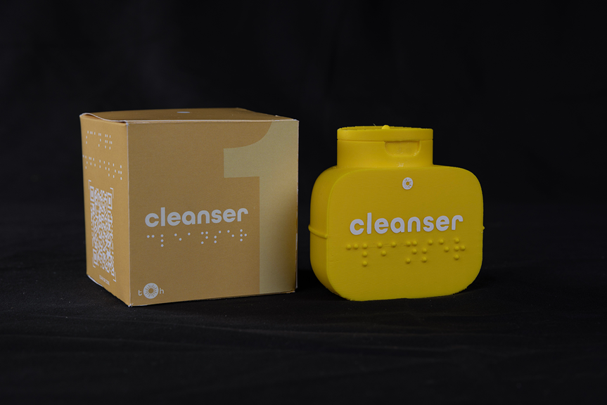 Square packaging and a yellow bottle, both with text that reads ‘cleanser’. There is braille on the packaging and bottle.