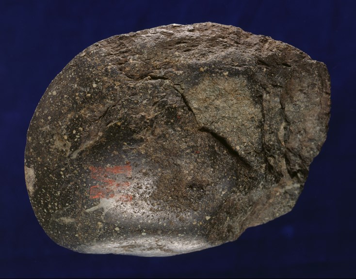 Photograph of a piece of greenstone against a dark backdrop