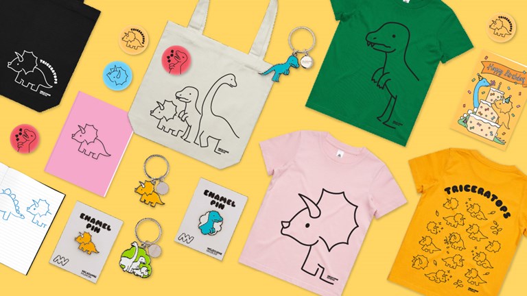 Dino Gang mechandise including cute and colourful shirts, bags, pins and keyrings.