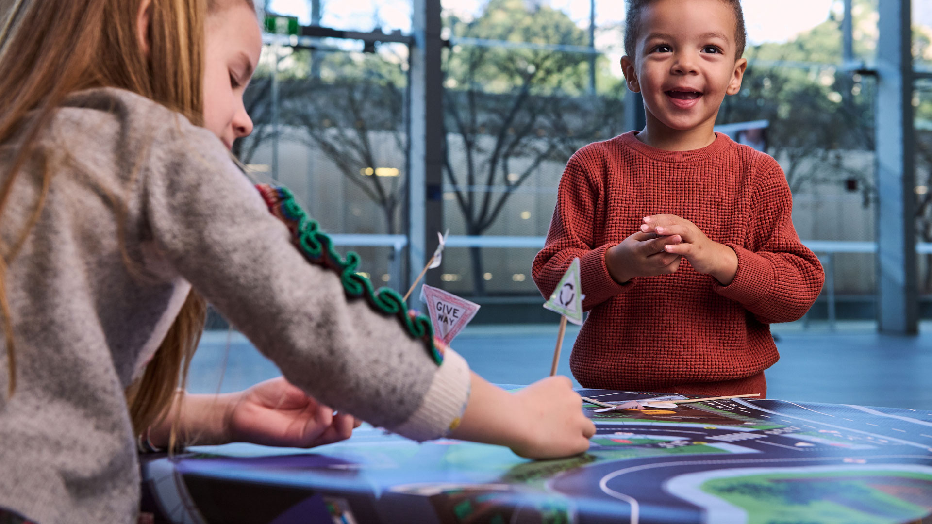Two young children happily participate in an activity making miniature road signs.