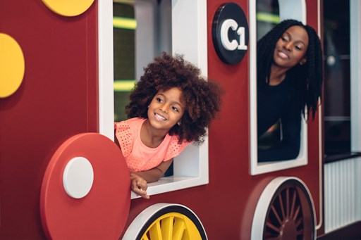 Girl and her mother looking out the windows of a pretend train