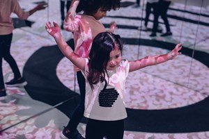 Children dancing in front of mirrors with projections on their arms and bodies